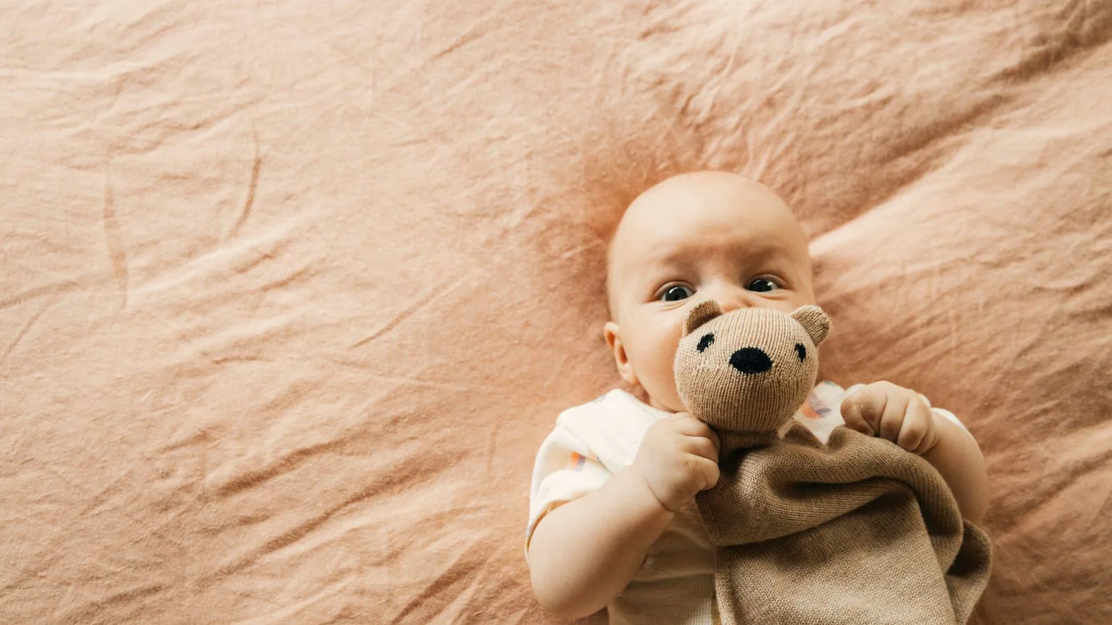 Photographie : un doudou en tissu posé sur une couverture